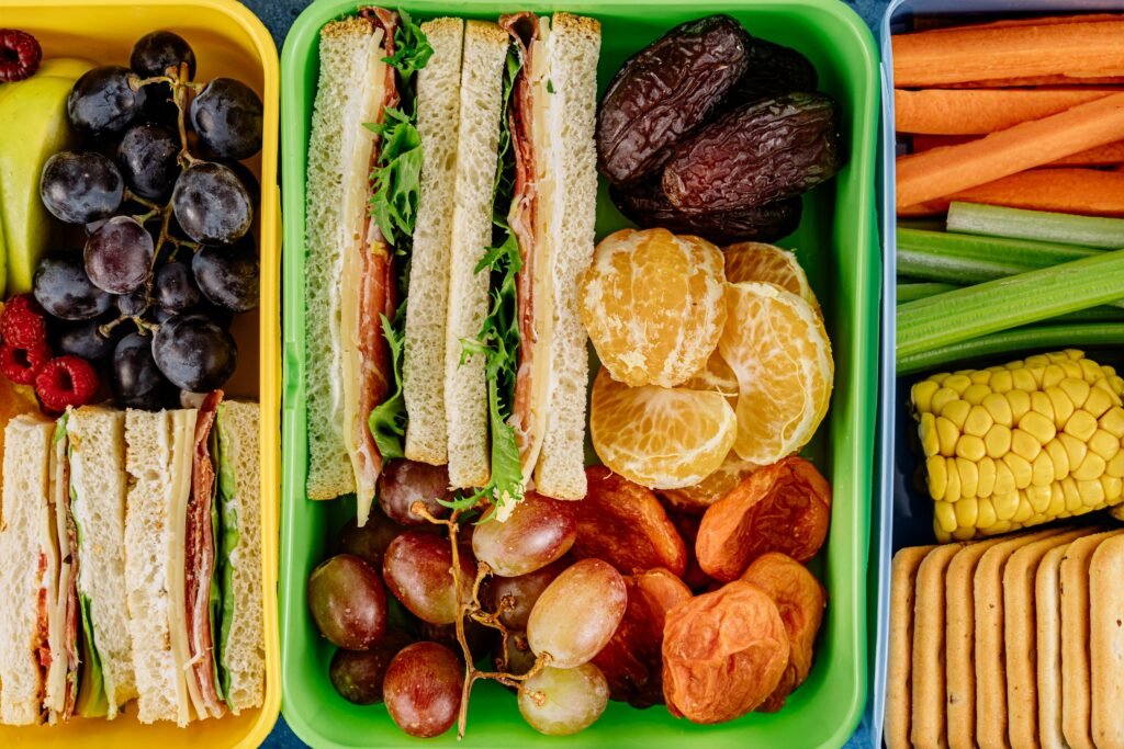 Colorful lunchbox filled with sandwiches, fresh fruits, and vegetables, perfect for a healthy meal.