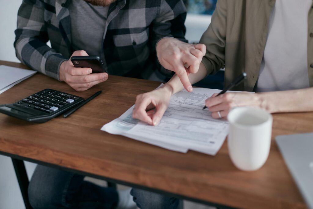 A couple analyzing financial documents and using a calculator at a home table.