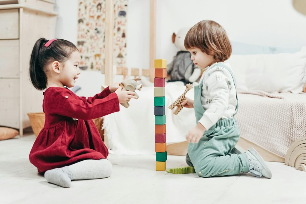 Two young children enjoying playtime with wooden blocks in a cozy indoor setting, fostering creativity and fun.